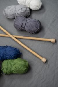 Skeins of yarn in various colours, alongside two knitting needles.