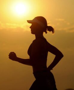 Silhouette of woman jogging in front of a sunset.