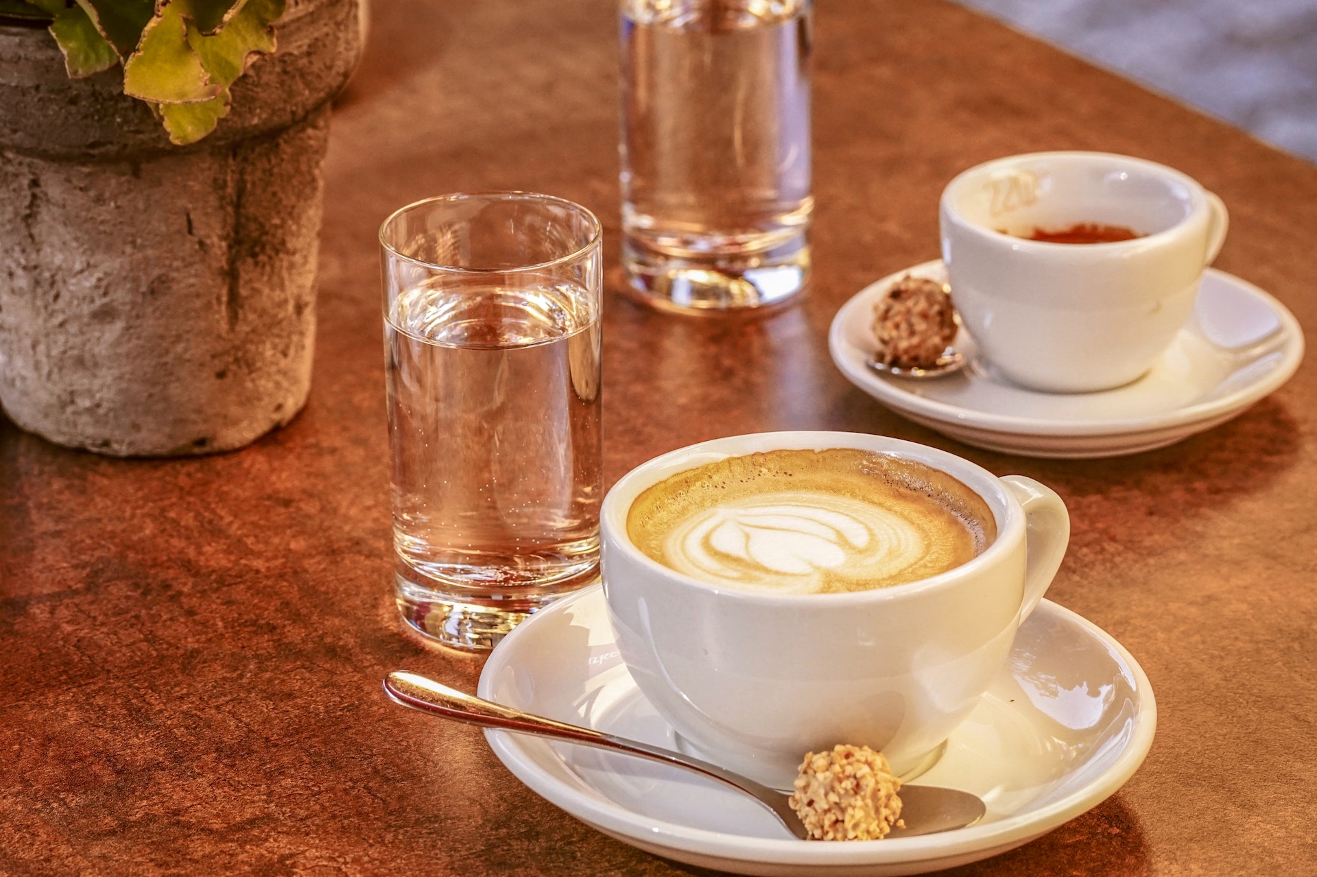 Two cups of coffee and two glasses of water on a table.